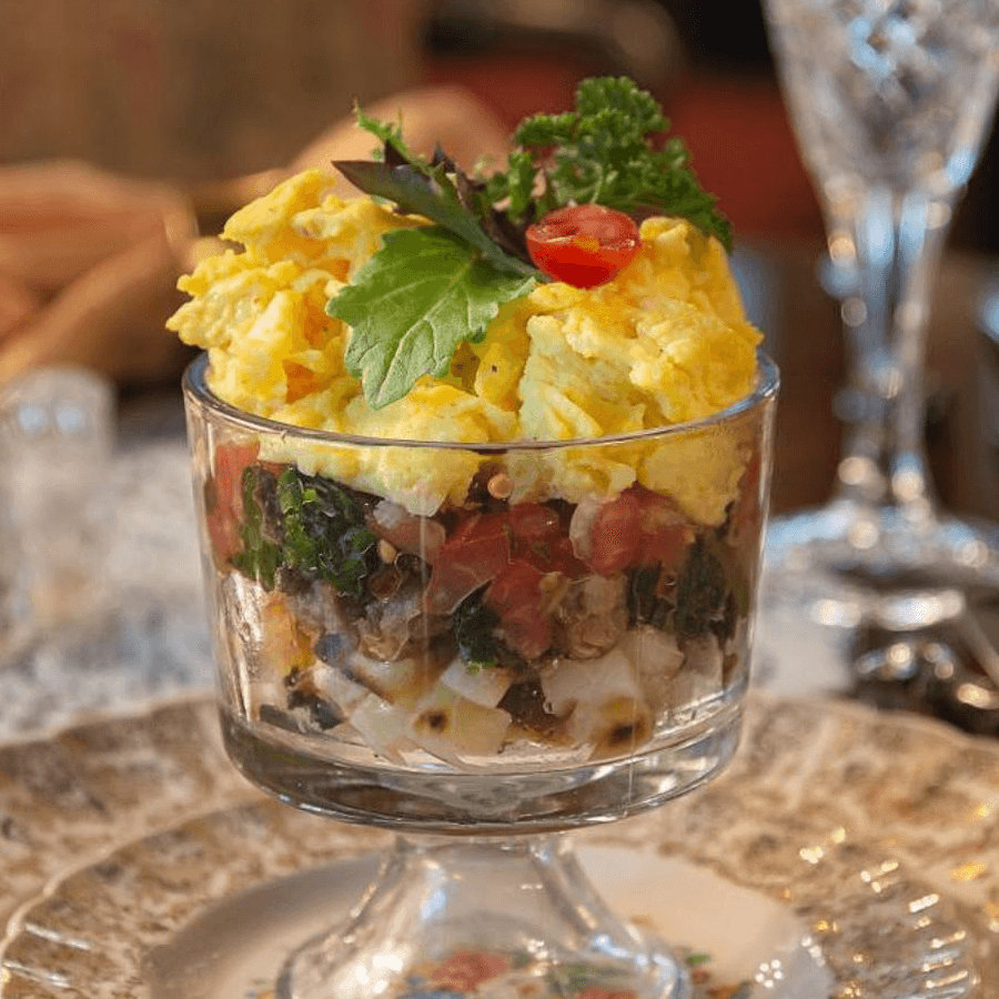 Breakfast of eggs and fruit served in fancy glass bowl