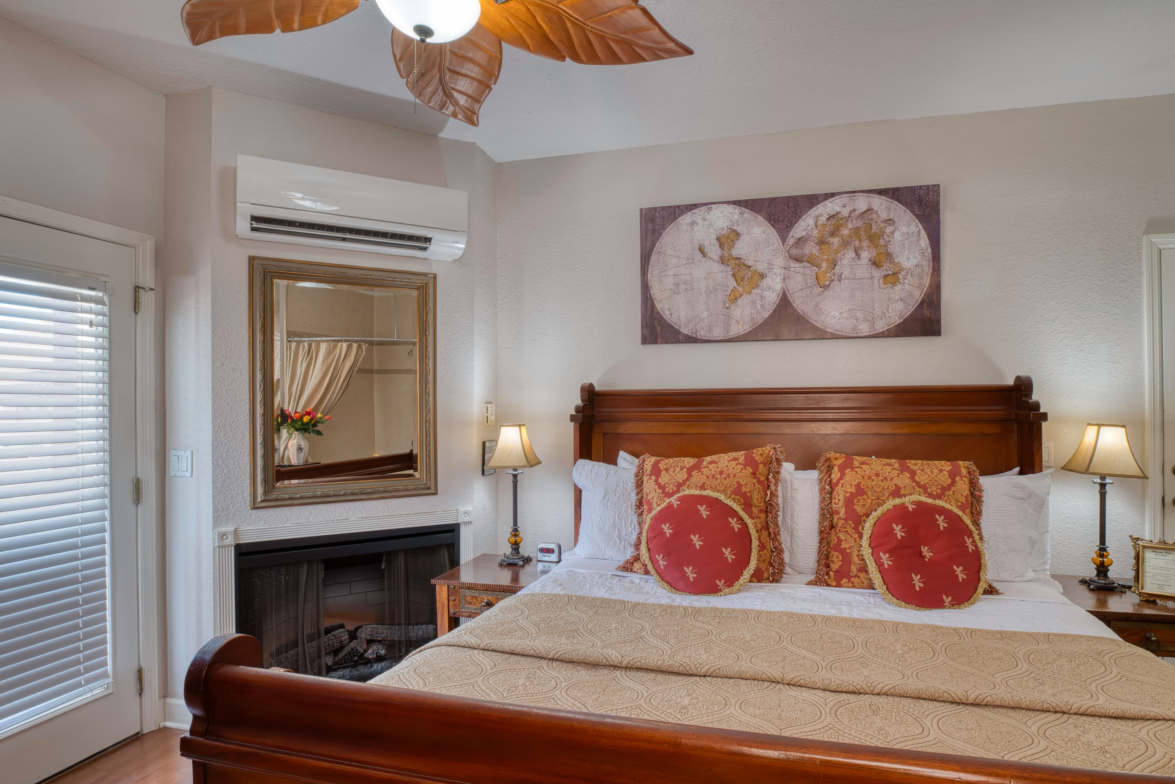 Wooden king-size bed flanked by nightstands with table lamps, electric fireplace, ceiling fan