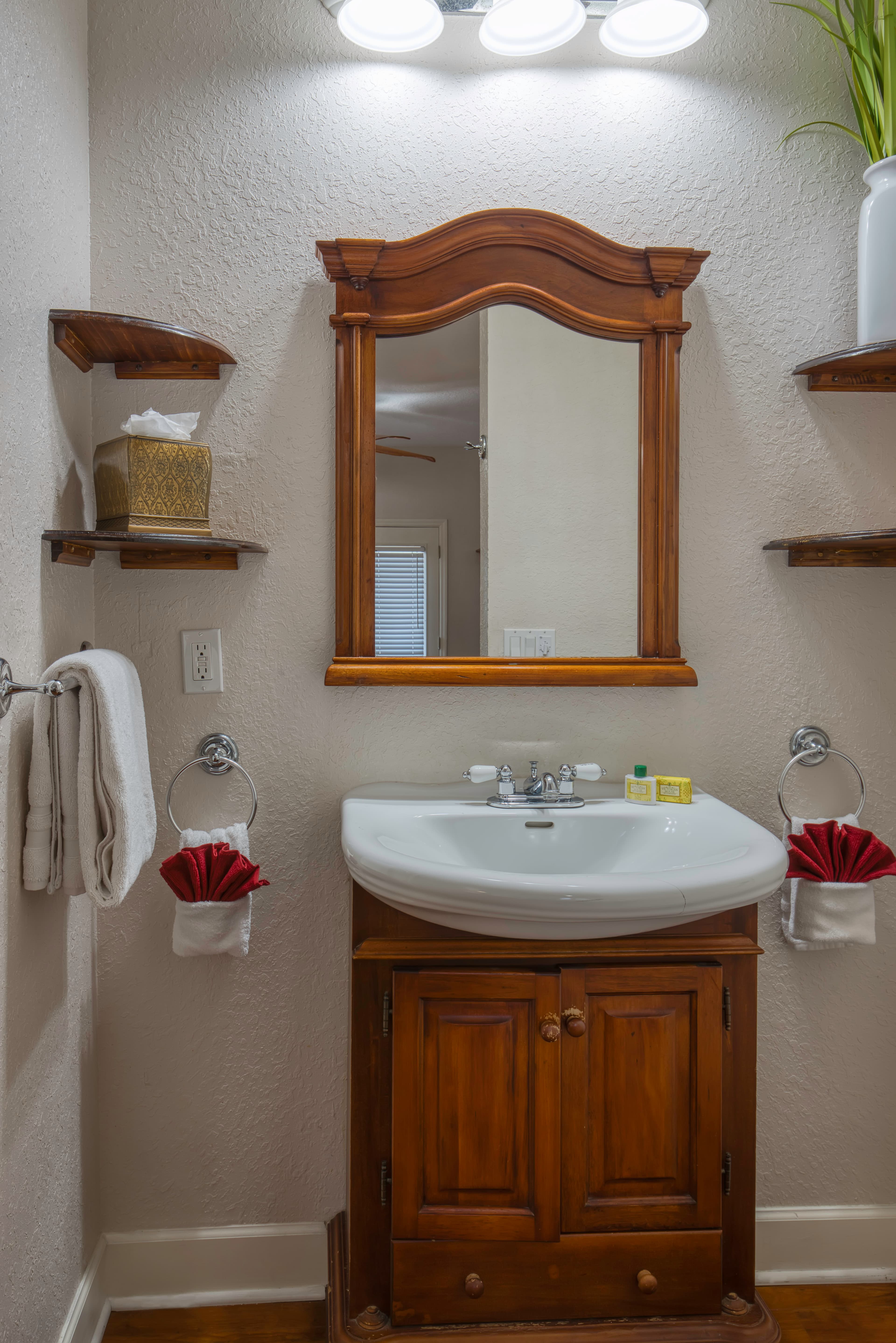 Bathroom with wooden vanity & white sink, coordinating wooden framed mirror above sink