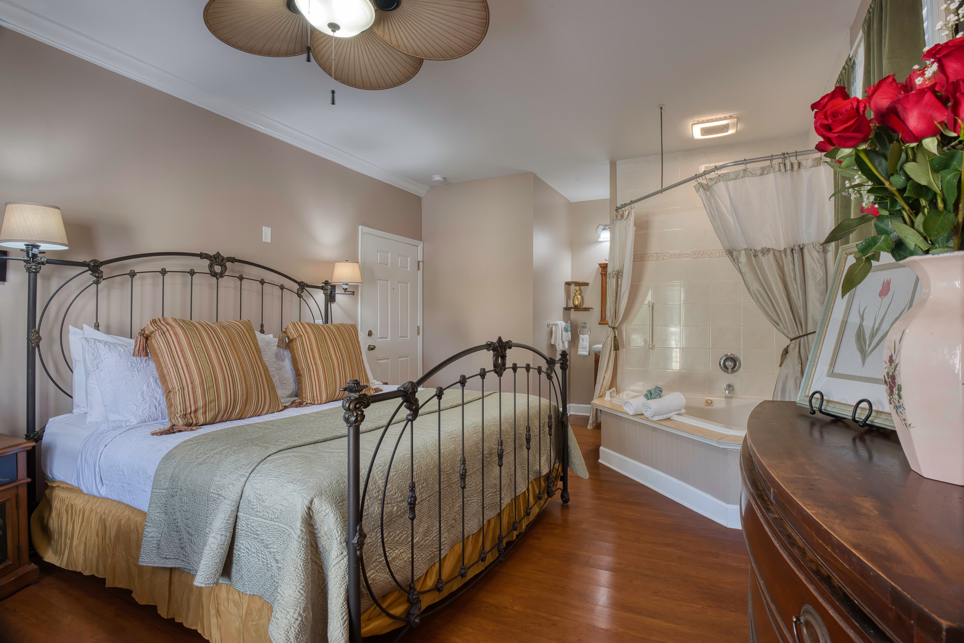 Romantic bedroom with king iron bed, hardwood floors, and in-room two-person Jacuzzi tub with shower