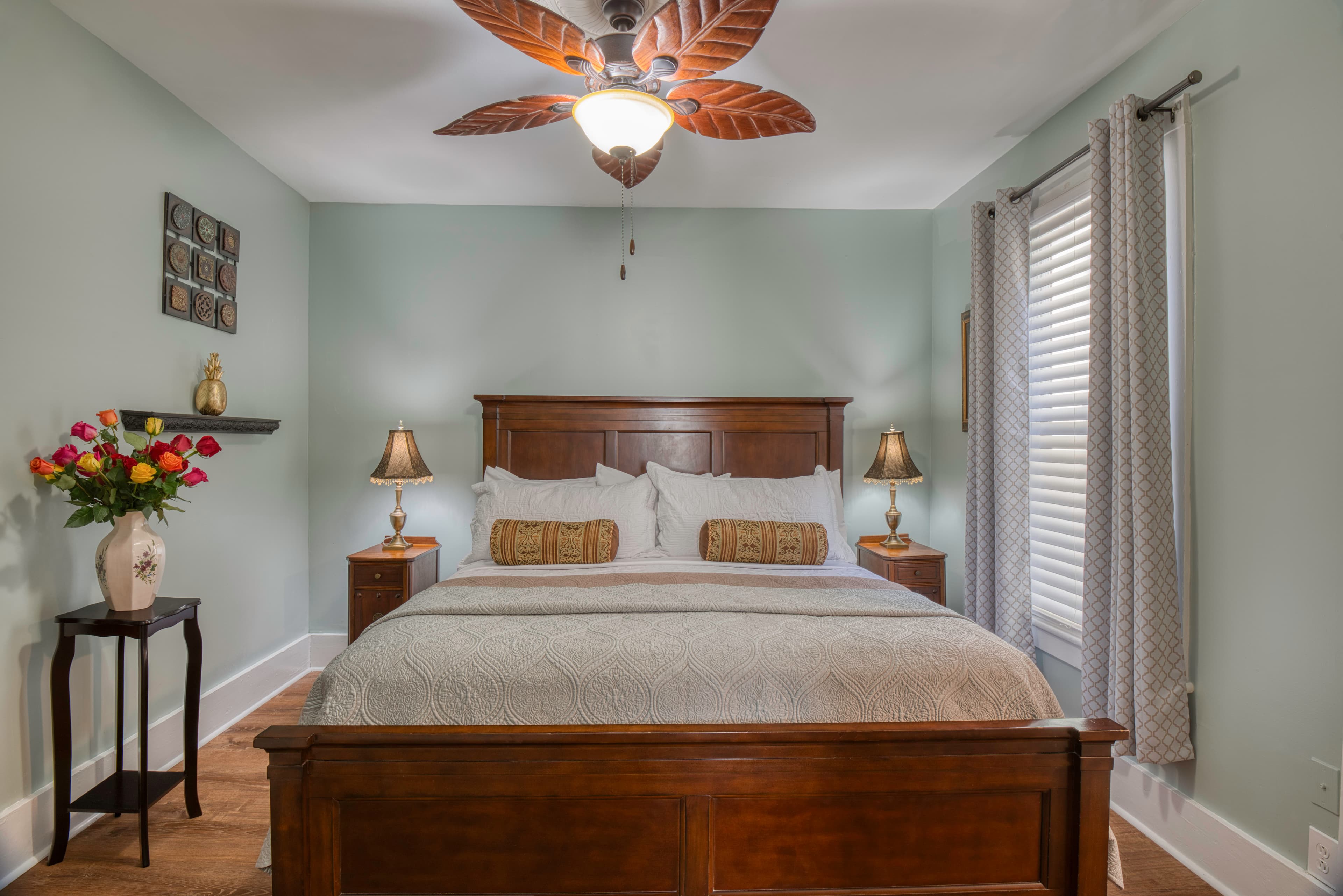 Tranquil, romantic bedroom with wooden king bed, nightstands with table lamps, ceiling fan