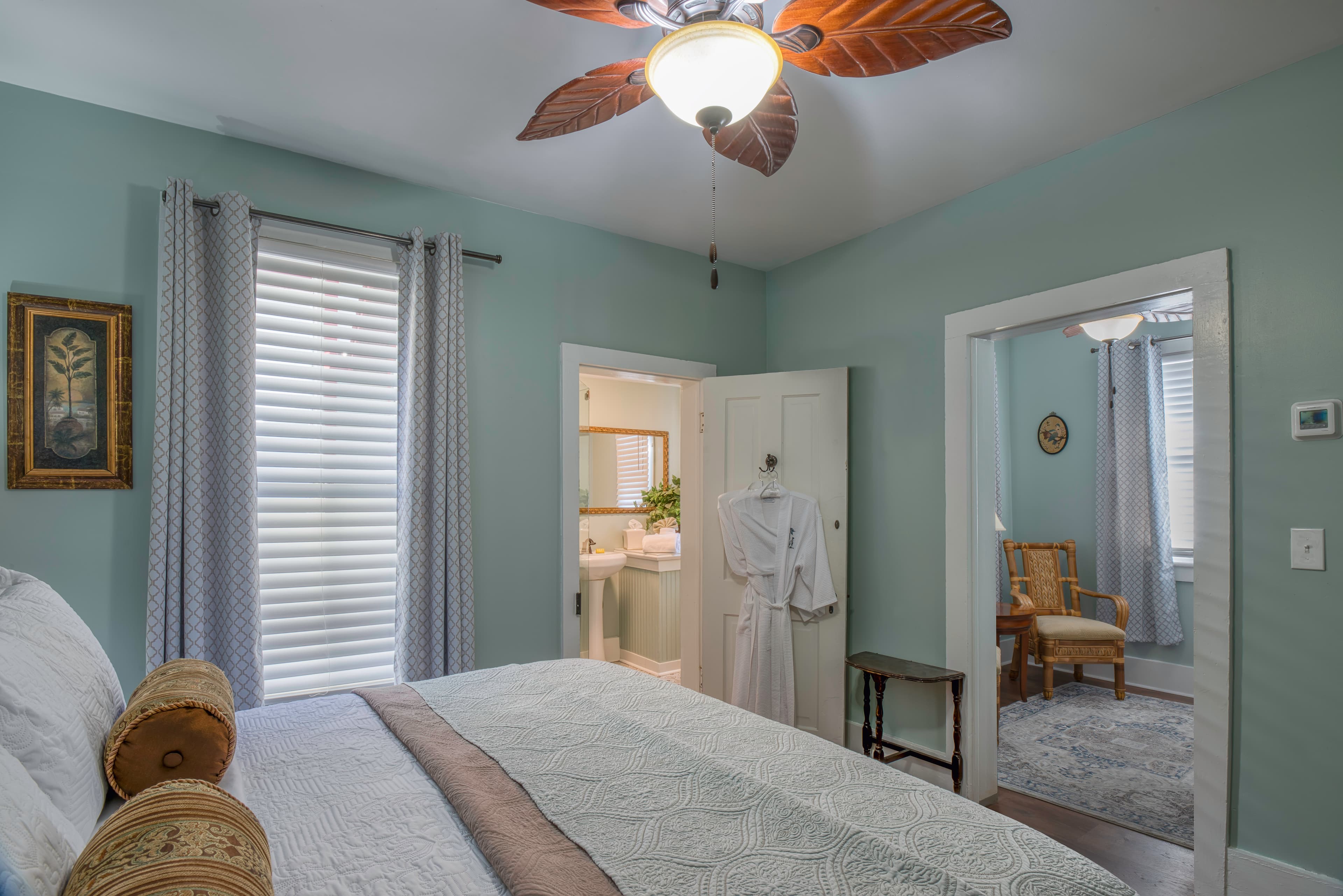 Bedroom in serene shades of light blue & white, king bed, doorways into bathroom & living area
