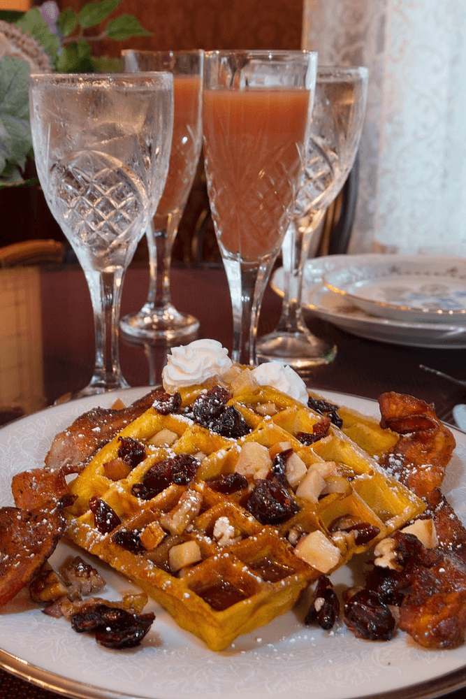 Waffles with fruit and syrup, and tall glass of juice