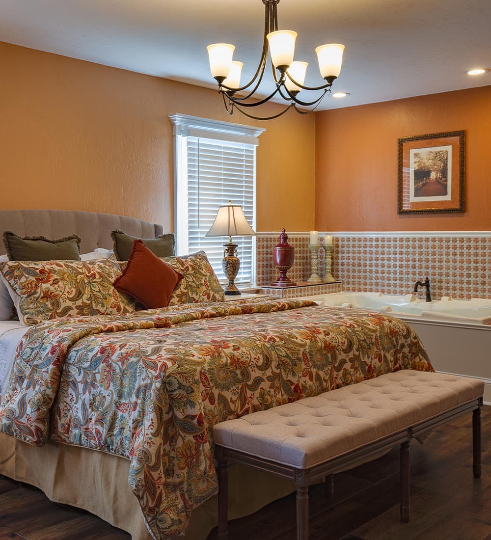 A cozy bedroom featuring a large bed with decorative bedding, a bedside lamp, and a serene color palette.