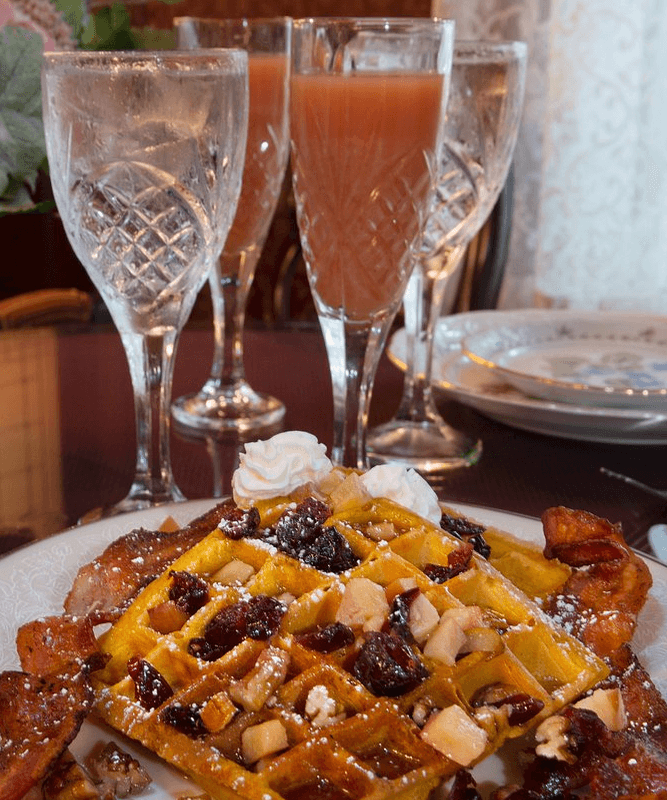 Waffles with fruit and syrup, and tall glass of juice