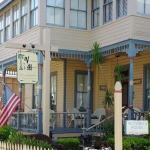 Victorian-style house with an American flag and a sign that reads "Victorian House." Victorian-style house with an American flag and a sign that reads "Victorian House."