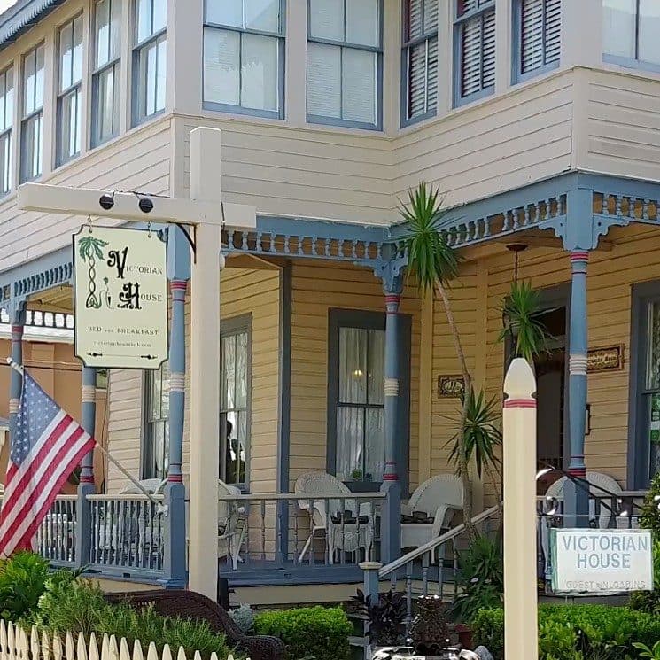 Victorian house bed and breakfast featuring a sign and decorative porch with an American flag.
