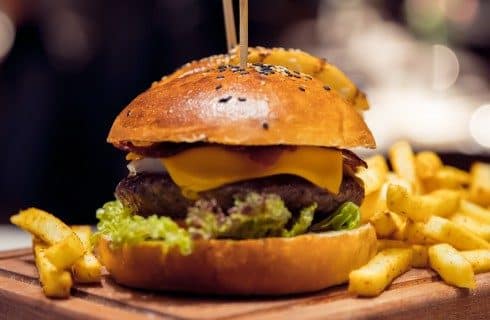 A delicious cheeseburger on a wooden board with golden french fries