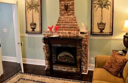 Sitting room with plush couch and brick fireplace flanked with two tapestries