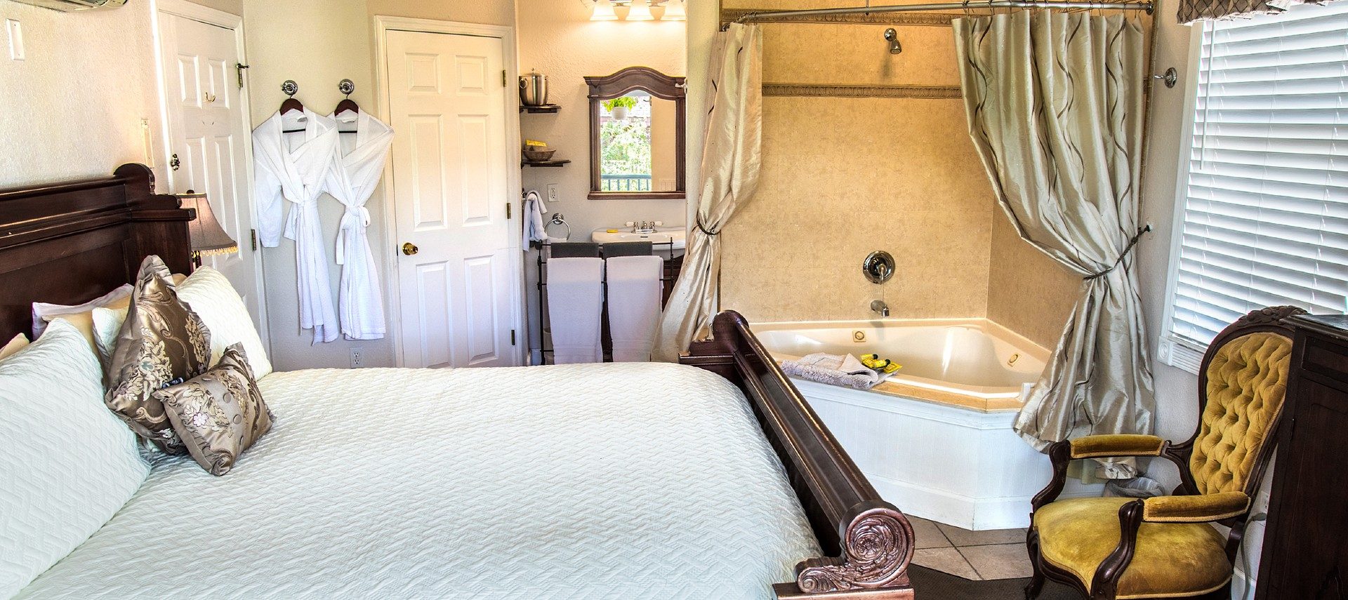 Bedroom featuring large sleigh bed, corner jacuzzi tub and single sink vanity with mirror